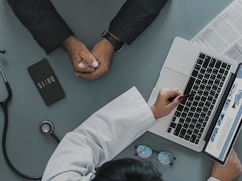 Een arts aan een bureau met een laptop en een stethoscoop